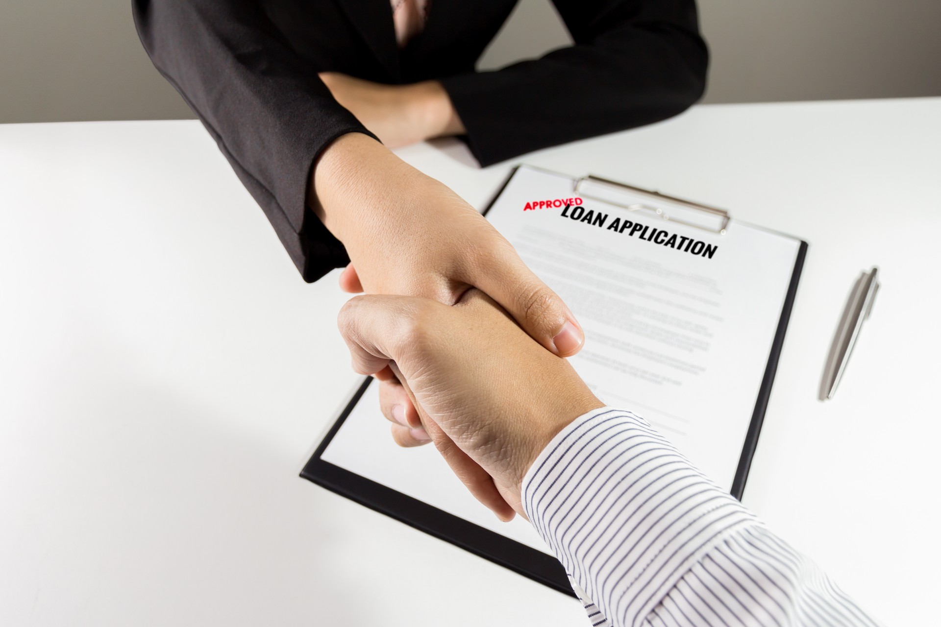 Top view banker and customer handshake over the loan application